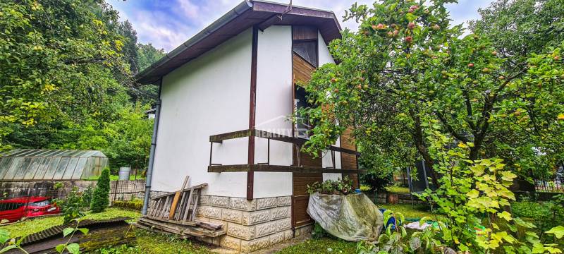 Ein Ferienhaus in Mojša, umgeben von einem grünen Garten und Obstbäumen.