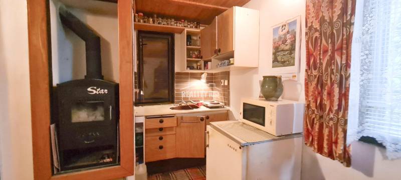 Hütte mit Küche, Herd, Mikrowelle, Heizung, Vorhänge, Schränke und Wanddekoration.