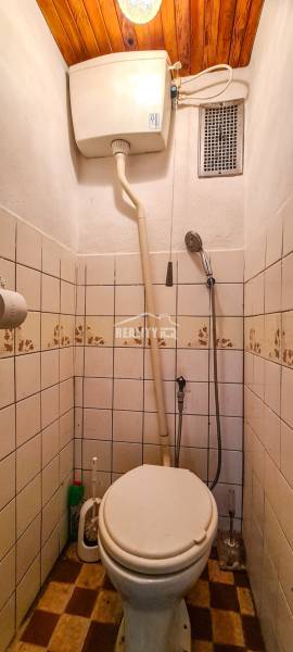 Kleines Badezimmer in der Hütte mit Toilette, Fliesen und Holzdecke.