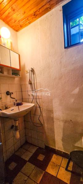 Badezimmer in der Hütte mit Waschbecken, Holzdecke und kleinem Fenster.