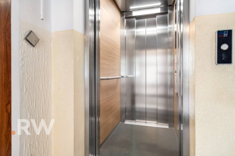Öffnen eines modernen Aufzugs auf der Etage eines Wohnhauses mit Holzdekor.