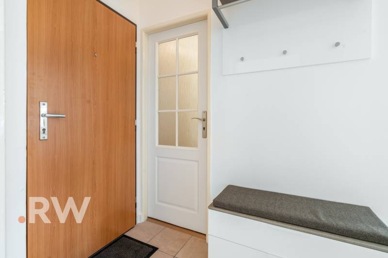 Weißes Interieur mit Türen und Bank in einer Zweizimmerwohnung.