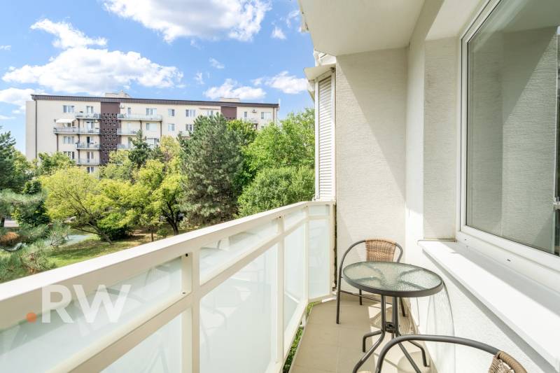 Der Balkon der 2-Zimmer-Wohnung bietet einen Blick auf Grünflächen und Wohnhäuser in Bratislava.