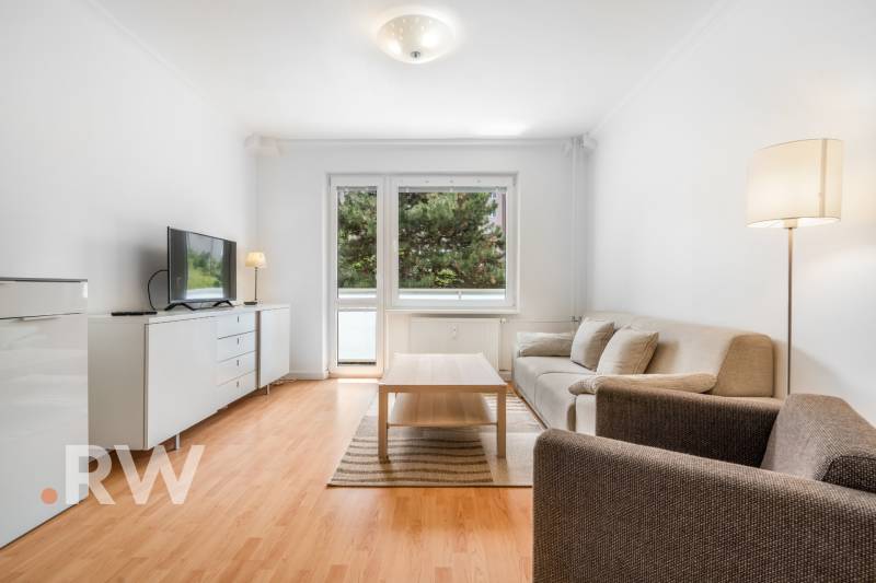 Wohnzimmer in einer 2-Zimmer-Wohnung mit bequemer Couch, Tisch und Fernseher, Holzboden-Dekor.
