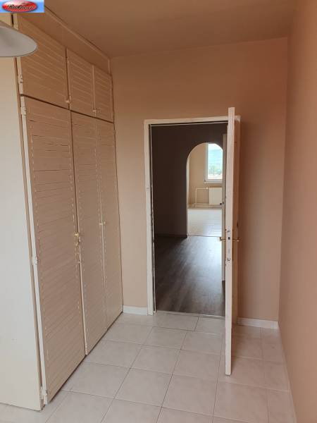 Innenraum einer 3-Zimmer-Wohnung mit Fliesen, Garderobenwand und Durchgang zu einem weiteren Raum.