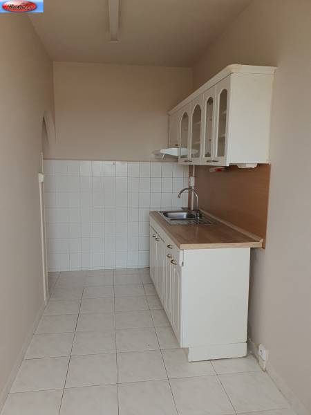 Küche mit weißen Schränken und Spüle in einer 3-Zimmer-Wohnung.