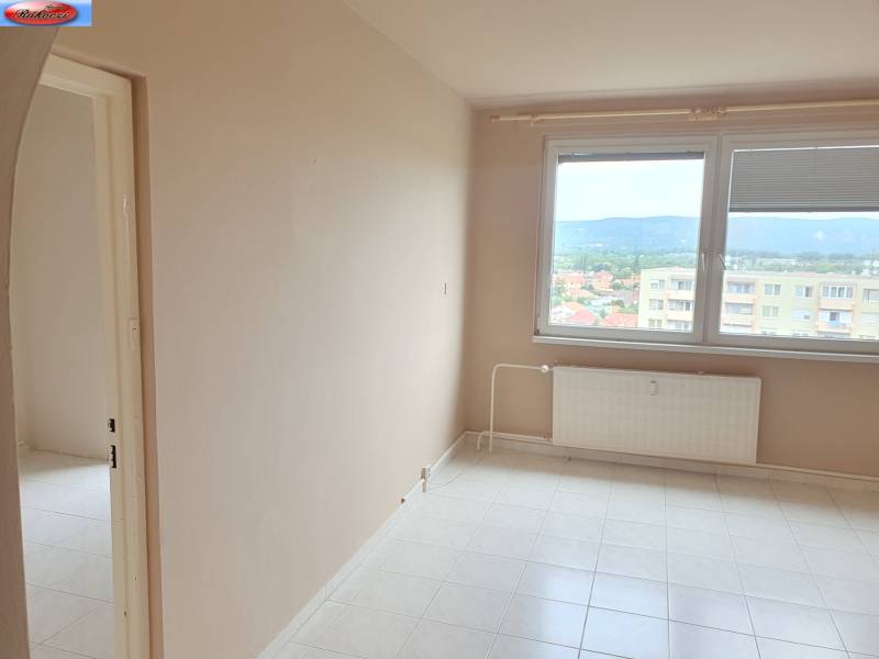 Ein leeres Zimmer in einer 3-Zimmer-Wohnung, mit einem Heizkörper unter einem großen Fenster.