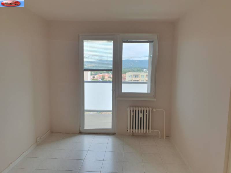 Ein Zimmer in einer 3-Zimmer-Wohnung mit Fliesen, Heizkörper und Balkontür.