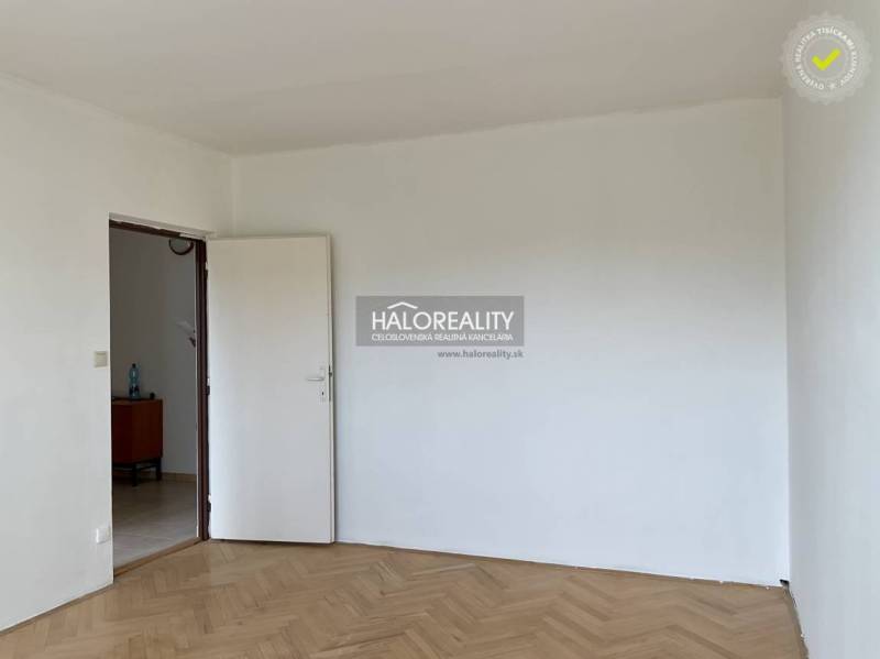 Leerer Raum mit weißer Wand und Holzboden in einer 3-Zimmer-Wohnung.