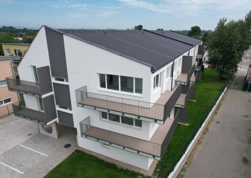 Ein Wohnhaus in der Muškátová-Straße mit Balkonen, grünem Rasen und Parkplätzen.