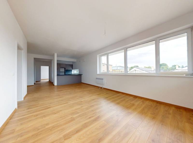 Geräumiges Wohnzimmer mit Holzboden und großen Fenstern in einer 3-Zimmer-Wohnung.