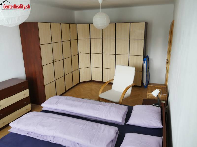 Schlafzimmer in einer 3-Zimmer-Wohnung mit einem großen Eckschrank und einem Sessel.