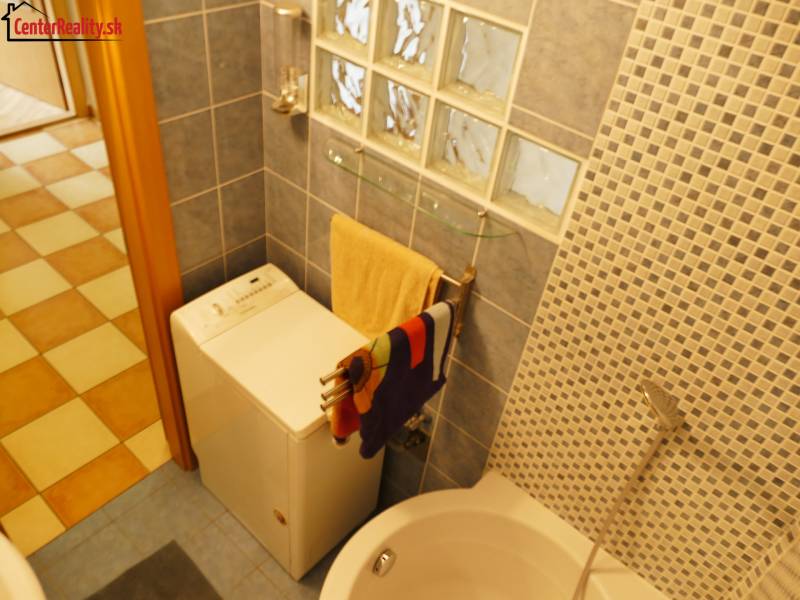 Badezimmer in einer 3-Zimmer-Wohnung mit Waschmaschine, Badewanne und Mosaikfliesenwand.