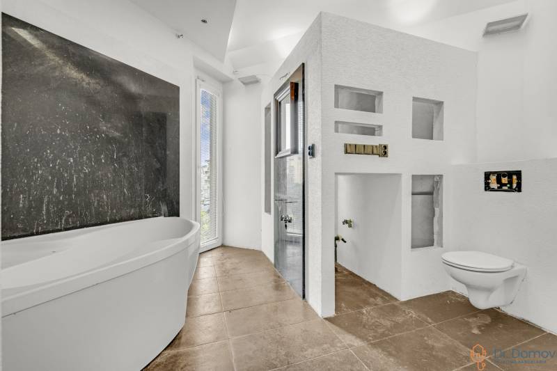 Weißes Badezimmer mit Badewanne, Dusche und hängendem WC in Geschäftsräumen.