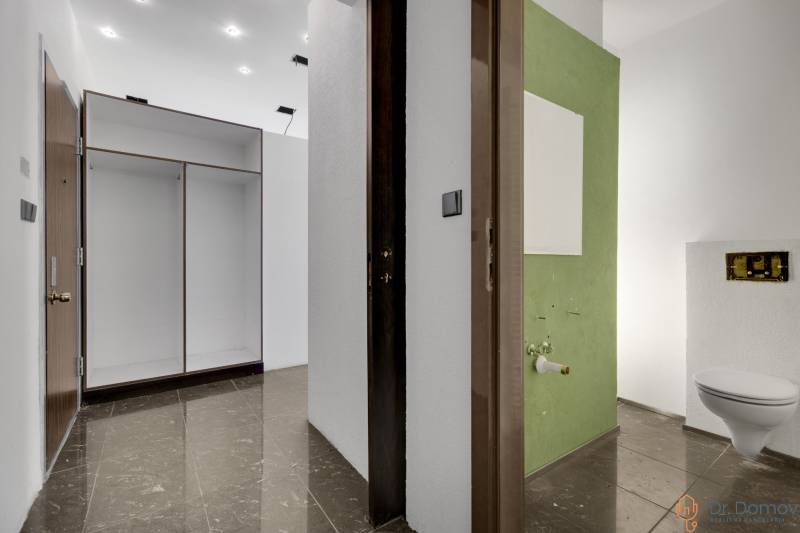 Flur mit Fliesen und Einbauschrank, der zu einem Badezimmer in Geschäftsräumen führt.