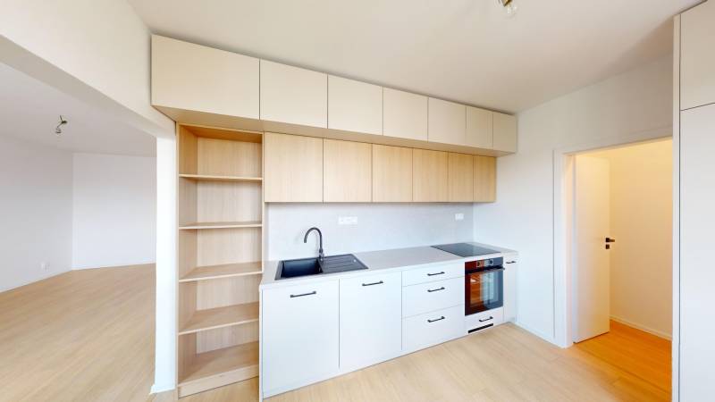 Küche in einer 2-Zimmer-Wohnung mit weißen Schränken und eingebautem Ofen.