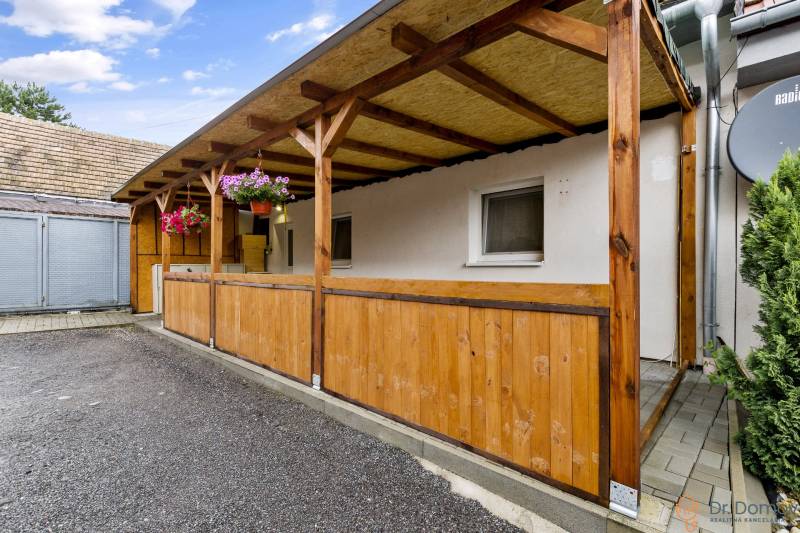 Holzterrasse bei einer 2-Zimmer-Wohnung in Malé Leváre, umgeben von Blumen.