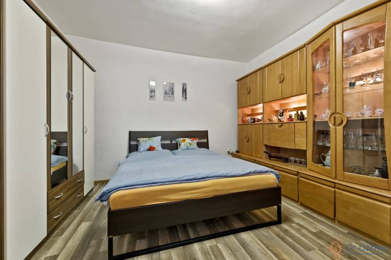 Schlafzimmer in einer 2-Zimmer-Wohnung mit Doppelbett, Schränken und dekorativem Regalsystem.