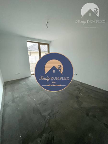Ein leerer Raum mit einem großen Fenster in einem Einfamilienhaus, mit unfertigem Boden.