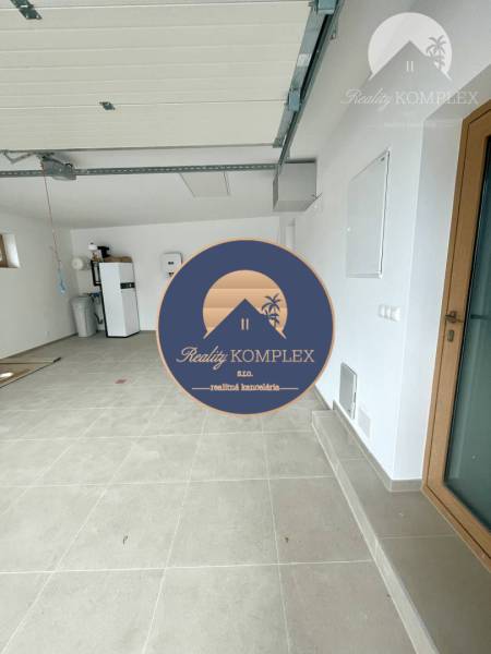 Eine Garage in einem Einfamilienhaus mit weißen Wänden und großen, hellen Fliesen.