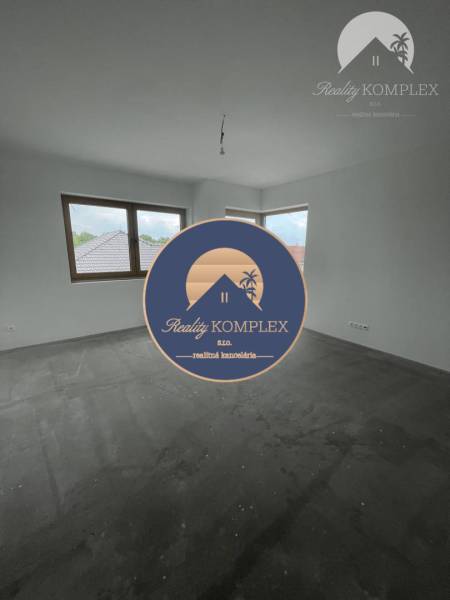 Ein leerer Raum mit Fenstern und Betonboden in einem Einfamilienhaus.