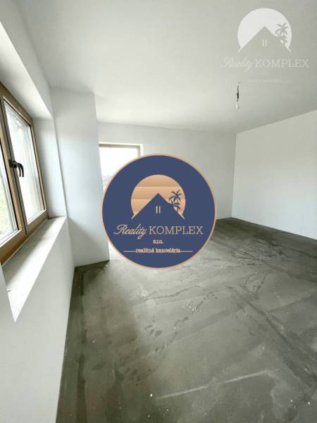 Ein unmöbliertes Zimmer in einem Einfamilienhaus mit Betonboden und Fenstern.
