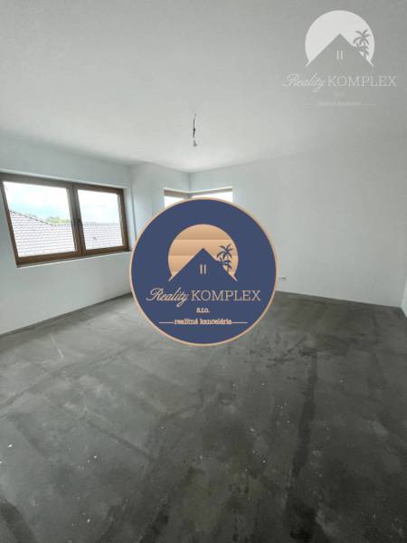 Ein leerer Raum mit grauem Boden und zwei Fenstern in einem Einfamilienhaus.