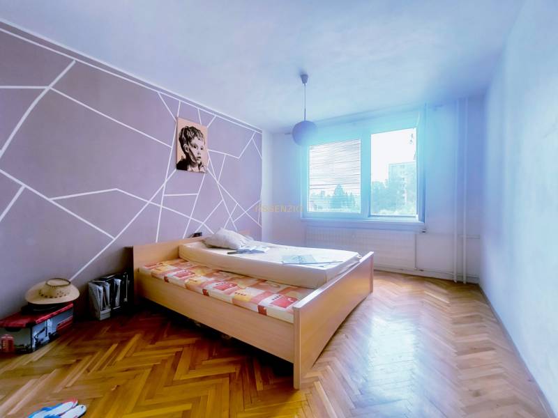 Schlafzimmer in einer 3-Zimmer-Wohnung mit Holzboden und auffälliger Wanddekoration.