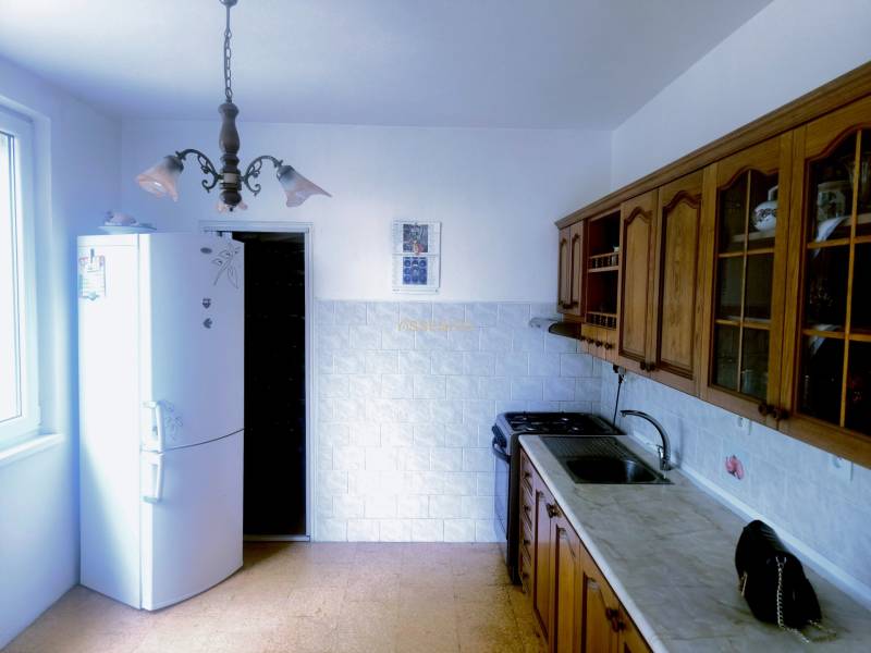 Küche in einer 3-Zimmer-Wohnung mit rustikalen Holzschränken und einem weißen Kühlschrank.