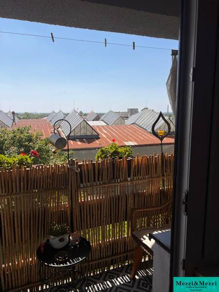 Balkon in einer 3-Zimmer-Wohnung mit Rattanmöbeln und Blick auf die Dächer.