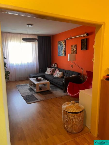 Wohnzimmer einer 3-Zimmer-Wohnung mit orangefarbener Wand, Sofa und Couchtisch.