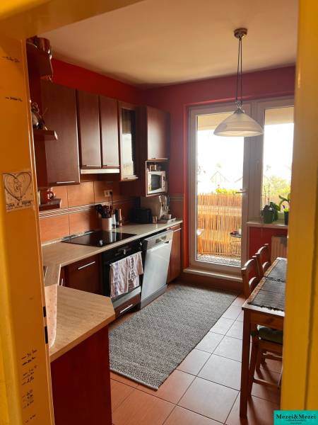 Küche mit Holzschränken und Essecke in einer 3-Zimmer-Wohnung.