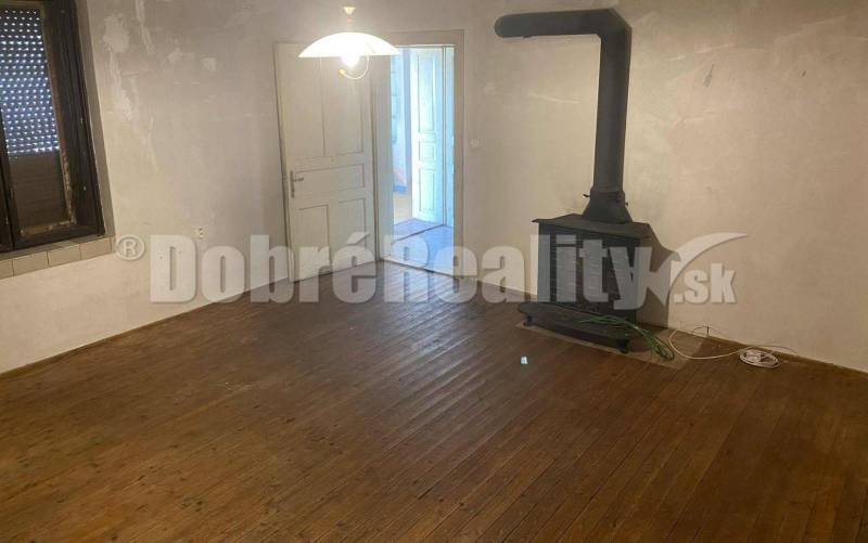 Ein Zimmer mit Holzboden und Kachelofen in einem Einfamilienhaus, einfaches Interieur.