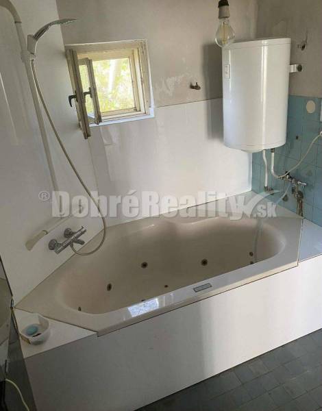 Badezimmer in einem Einfamilienhaus mit Badewanne, Dusche und Boiler zur Wassererwärmung.