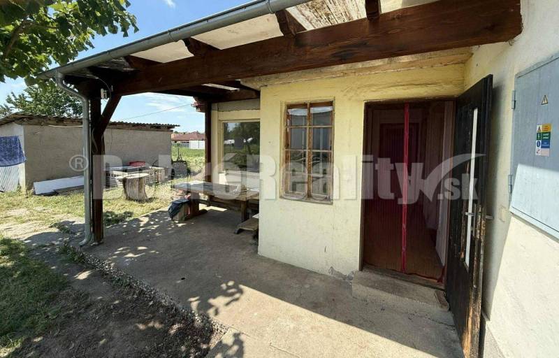 Der Hof des Einfamilienhauses in Mojmírovce, mit einem Unterstand, einem Tisch und Holzelementen.