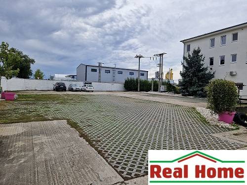 Parkplatz in der Šamorínska-Straße bei Lagerhäusern und Hallen, mit Kennzeichnung des Immobilienbüros.