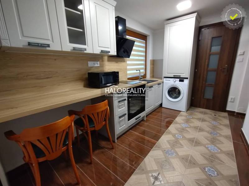 Einzimmerwohnung mit Kochnische, Waschmaschine und Holzstühlen.