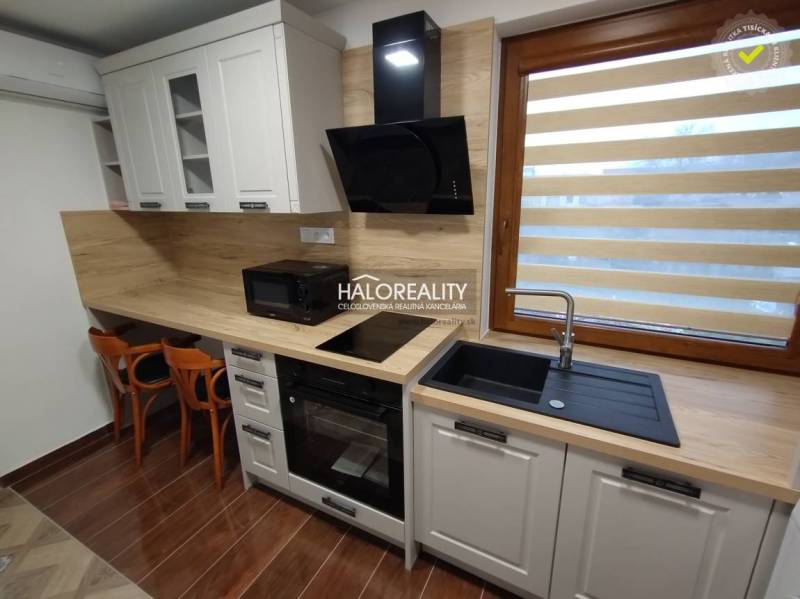 Küche in einem Studio-Apartment mit Holzelementen, ausgestattet mit einem Ofen, Spüle und Geräten.