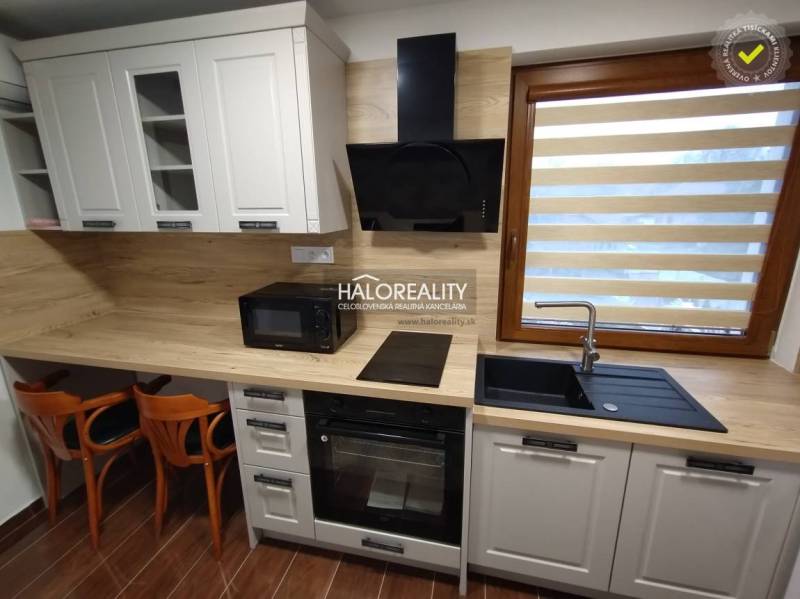 Küchenbereich in einem Studio-Apartment mit Holzmöbeln und Geräten.