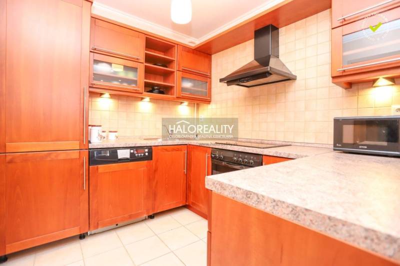 Küche in einer 2-Zimmer-Wohnung mit Holzküche und Geräten, einschließlich Mikrowelle.