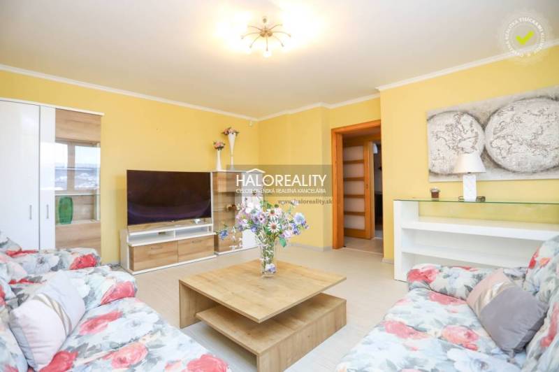 Wohnzimmer in einer 2-Zimmer-Wohnung mit einem bequemen Sofa, einem Tisch und einem Fernseher.