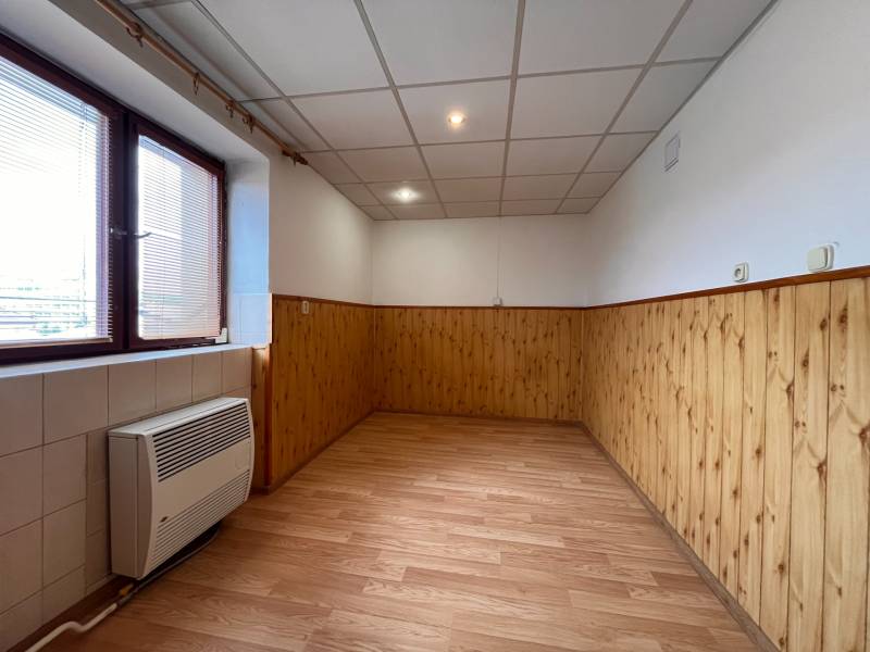 Ein Zimmer mit Holzverkleidung, schwimmendem Boden und Fenster in einer 2-Zimmer-Wohnung.