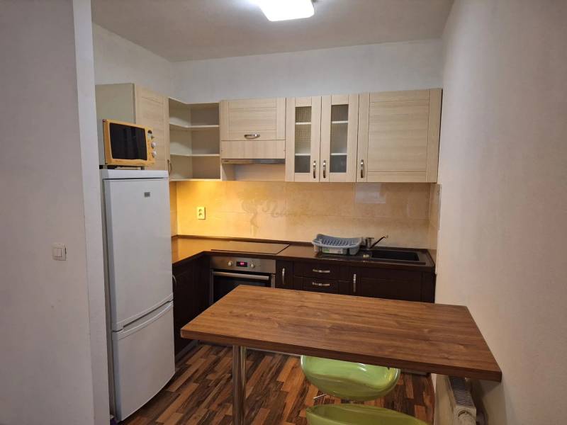 Küche mit Geräten, Holzarbeitsplatte und Esstisch in einer Zweizimmerwohnung.