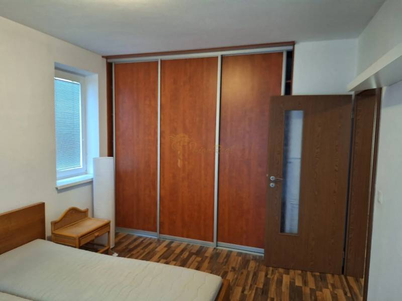 Schlafzimmer in einer 2-Zimmer-Wohnung mit Holzboden, Kleiderschrank und Bett.