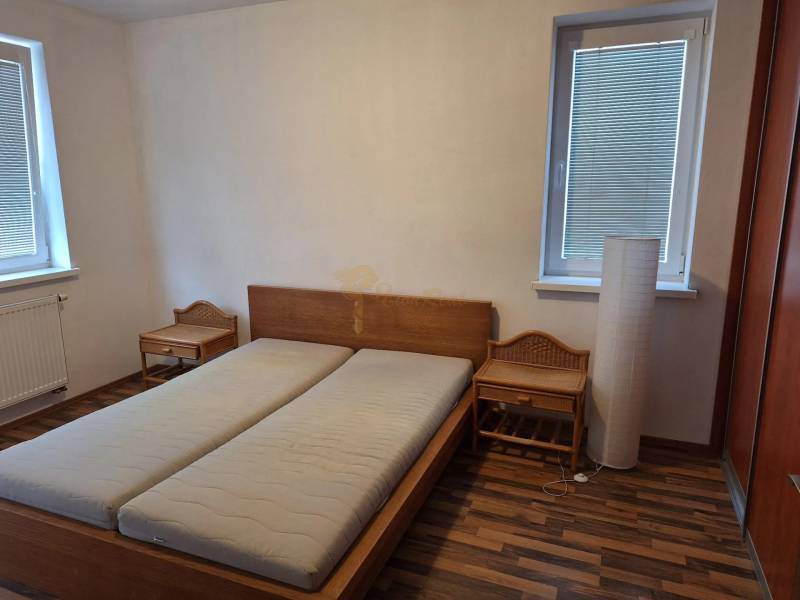 Schlafzimmer in einer 2-Zimmer-Wohnung mit einem Holzbett und Nachttischen.