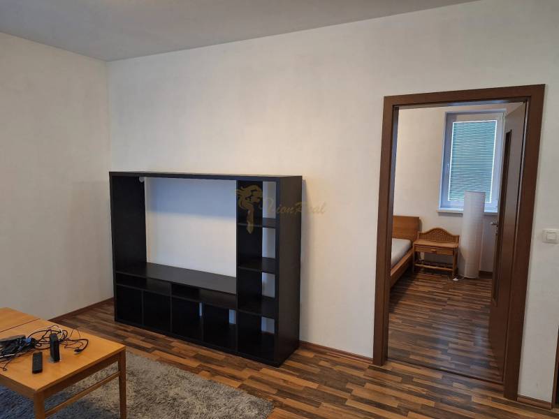 Holzboden, schwarzes Regal, Eingang zum Schlafzimmer in einer Zweizimmerwohnung.
