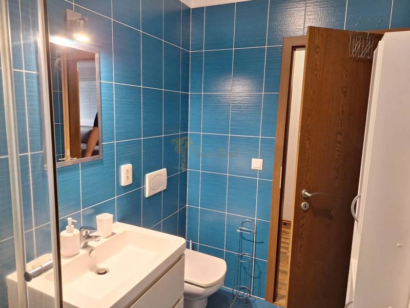 Badezimmer mit Dusche, Waschbecken und blauen Fliesen in einer 2-Zimmer-Wohnung.
