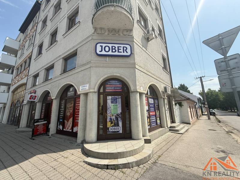 Geschäftsräume in Komárno in der Petőfi-Straße mit sonniger Fassade und Werbeschildern.