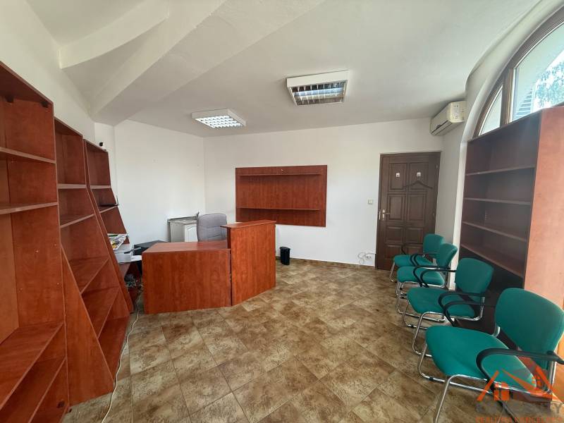 Büros mit Holzmöbeln und grünen Stühlen, Fliesenboden, Fenster mit Bogen.
