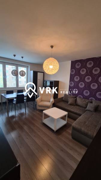 Wohnzimmer in einer Zweizimmerwohnung mit Sofa, Sessel und Esstisch.